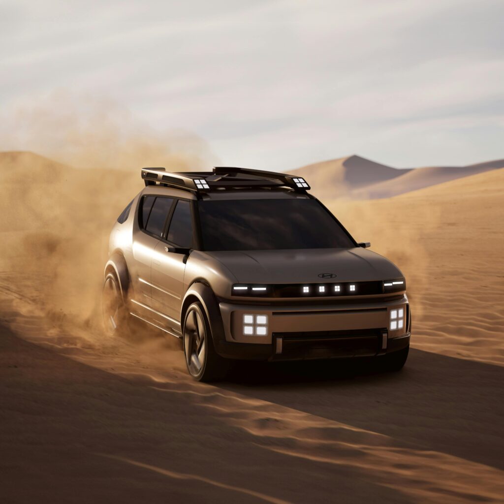 A futuristic SUV driving through desert sand, showcasing off-road capability.